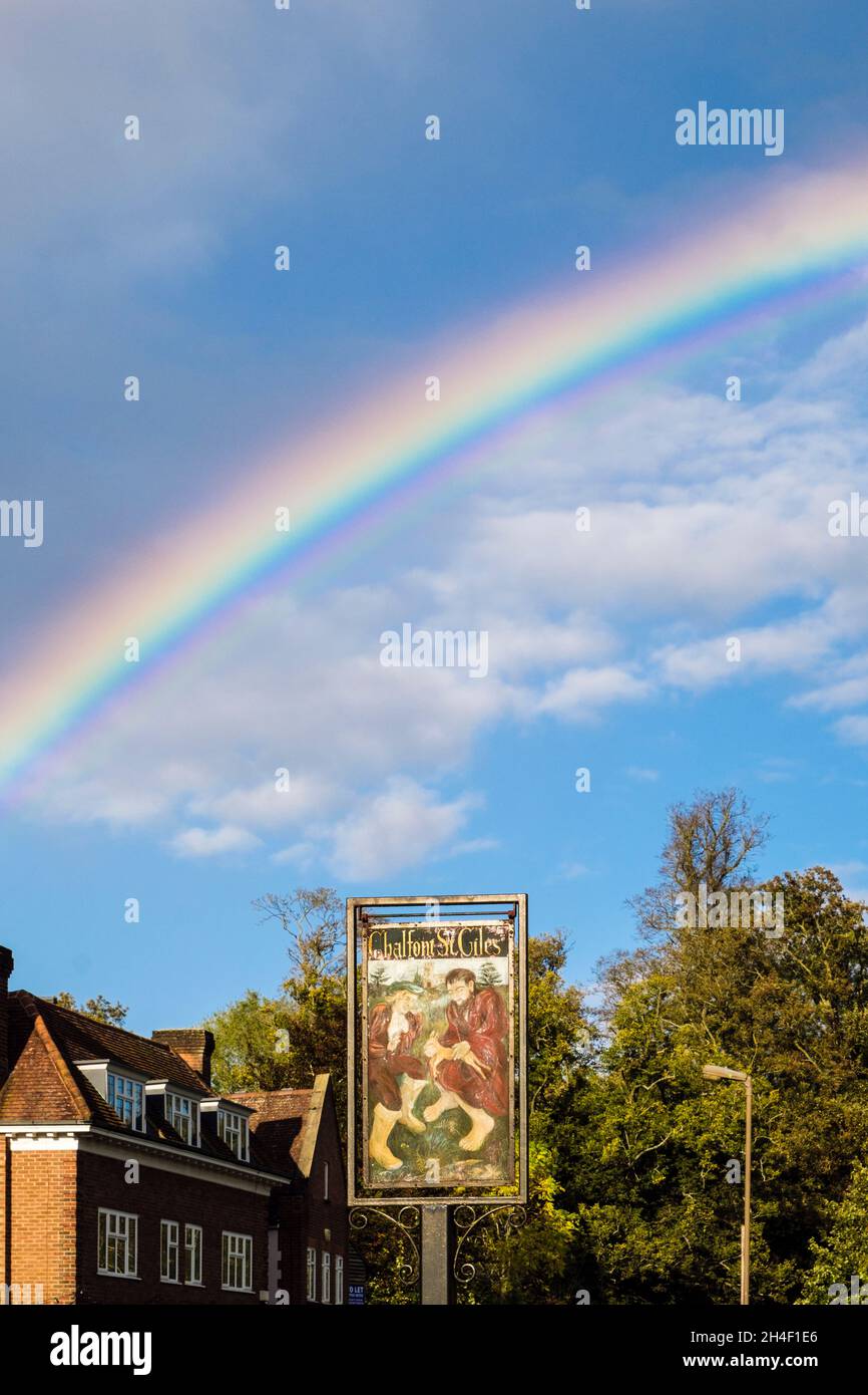 Arcobaleno pieno nel cielo sopra il segno del villaggio. High Street, Chalfont St Giles, Buckinghamshire, Inghilterra, Regno Unito, Regno Unito Foto Stock