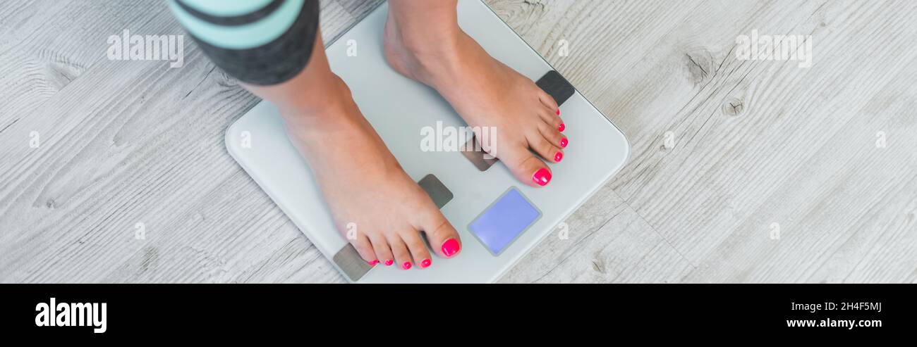vista ritagliata della donna a piedi nudi stima del peso su scale da pavimento, banner Foto Stock