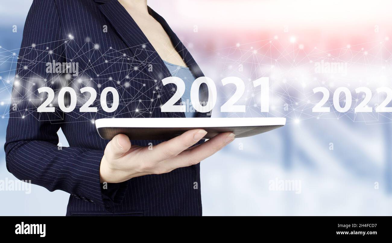 Benvenuto anno 2021. Business nuovo anno di concetto scheda. Tenere la compressa bianca con il segno ologramma digitale 2021 su sfondo sfocato chiaro. Successo nuovo yea Foto Stock