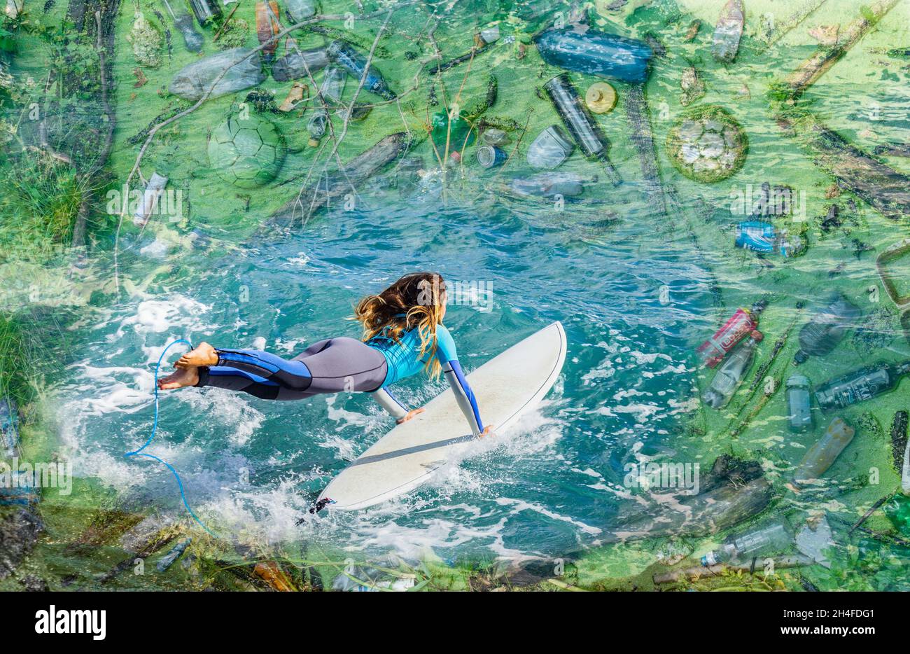 Giovane surfista femminile che salta nell'oceano circondato da rifiuti di plastica. Plastica oceanica, plastica, cambiamento climatico, inquinamento... concetto composito. Foto Stock