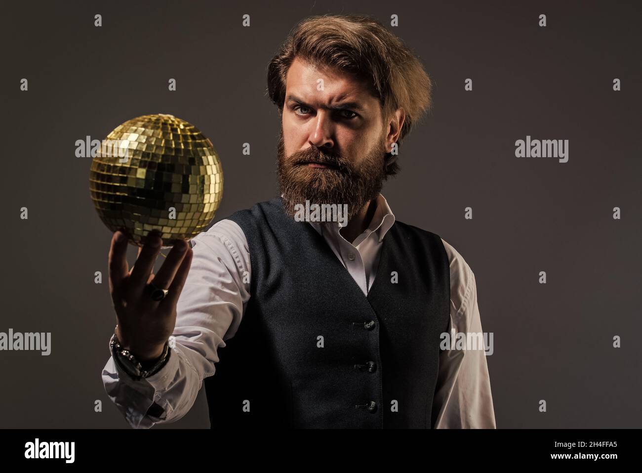 L'uomo maturo bearded tiene la sfera dorata della discoteca, concetto di vita notturna Foto Stock