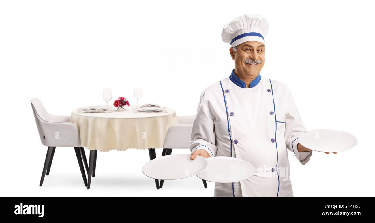 Chef allegro e maturo sorridendo e tenendo tre piatti di fronte ad un tavolo da ristorante isolato su sfondo bianco Foto Stock