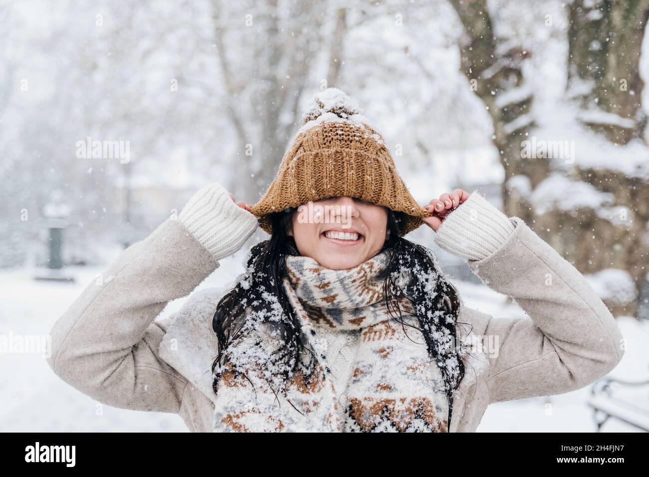 Ritratto di bella giovane donna in abiti invernali tirando il cappello giù sopra gli occhi. Foto Stock