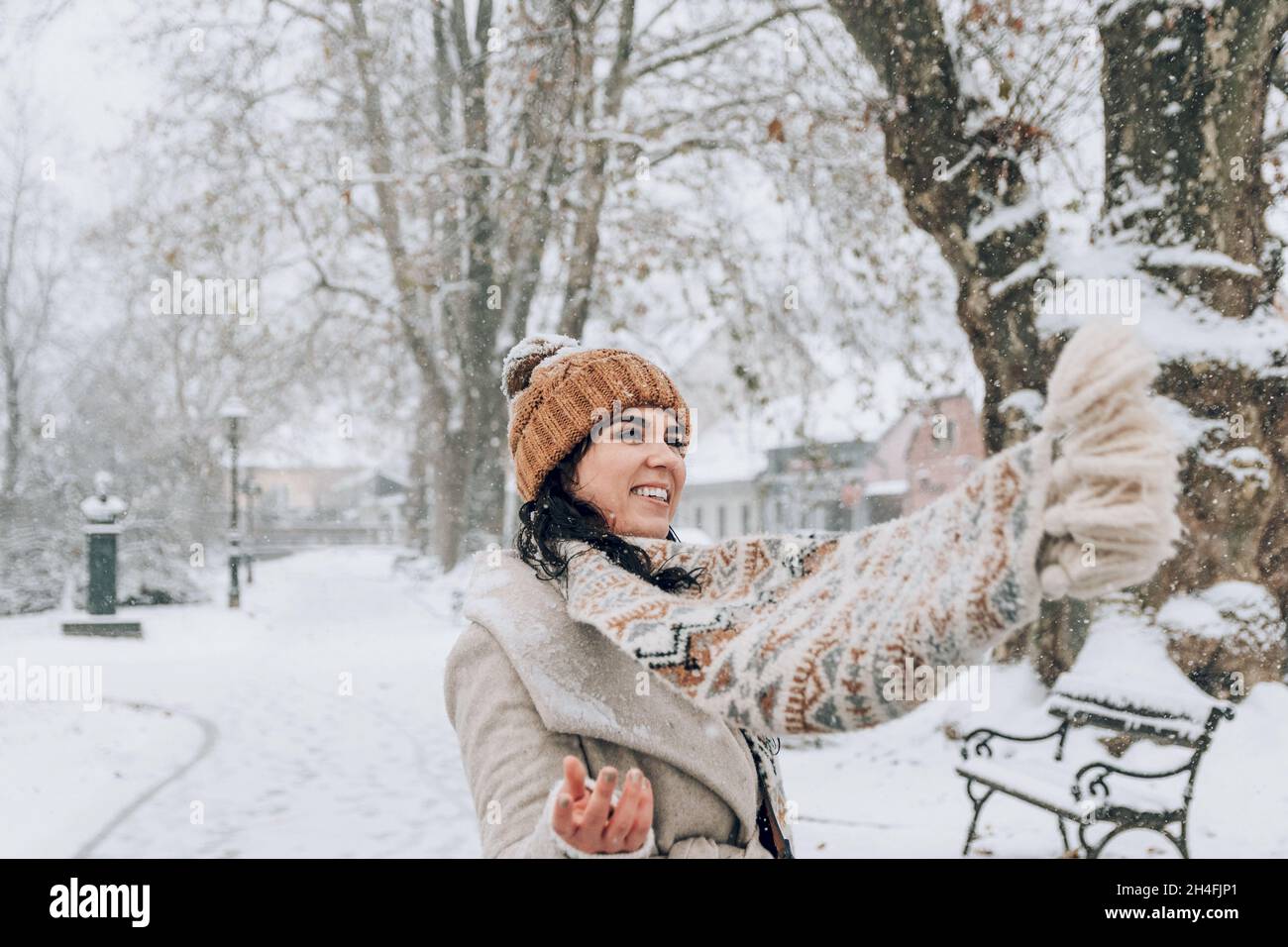 Ritratto di una bella giovane donna in eleganti abiti invernali in piedi nel parco nevoso. Foto Stock