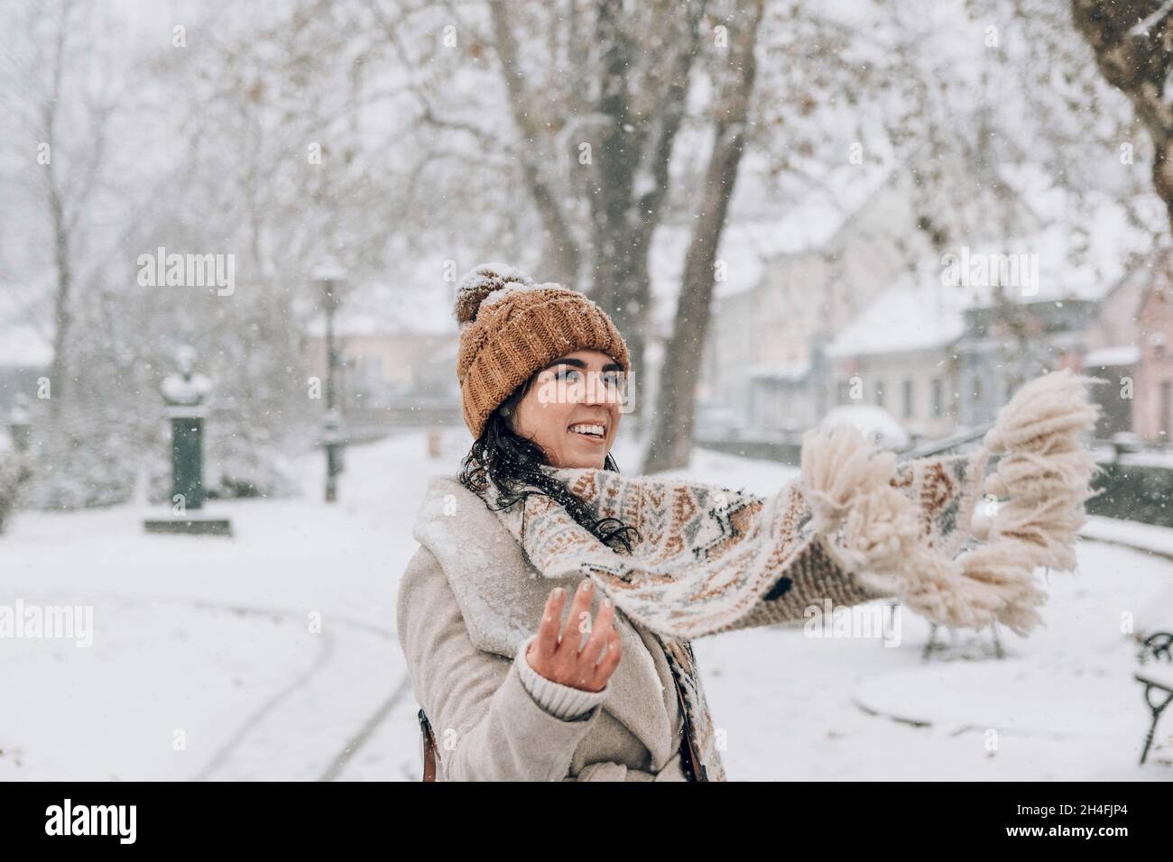 Ritratto di una bella giovane donna in eleganti abiti invernali in piedi nel parco nevoso. Foto Stock