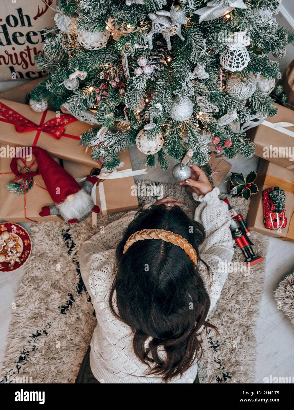 Vista dall'alto della donna con capelli scuri che si stendano davanti all'albero di Natale decorato. Foto Stock