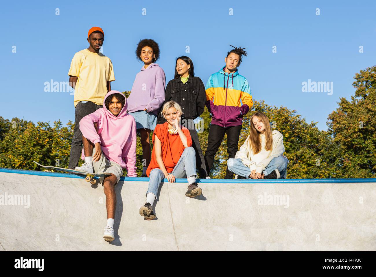 Gruppo multiculturale di giovani amici che si legano all'aperto e divertirsi - ragazzi alla moda e cool che si riuniscono al parco urbano skate Foto Stock