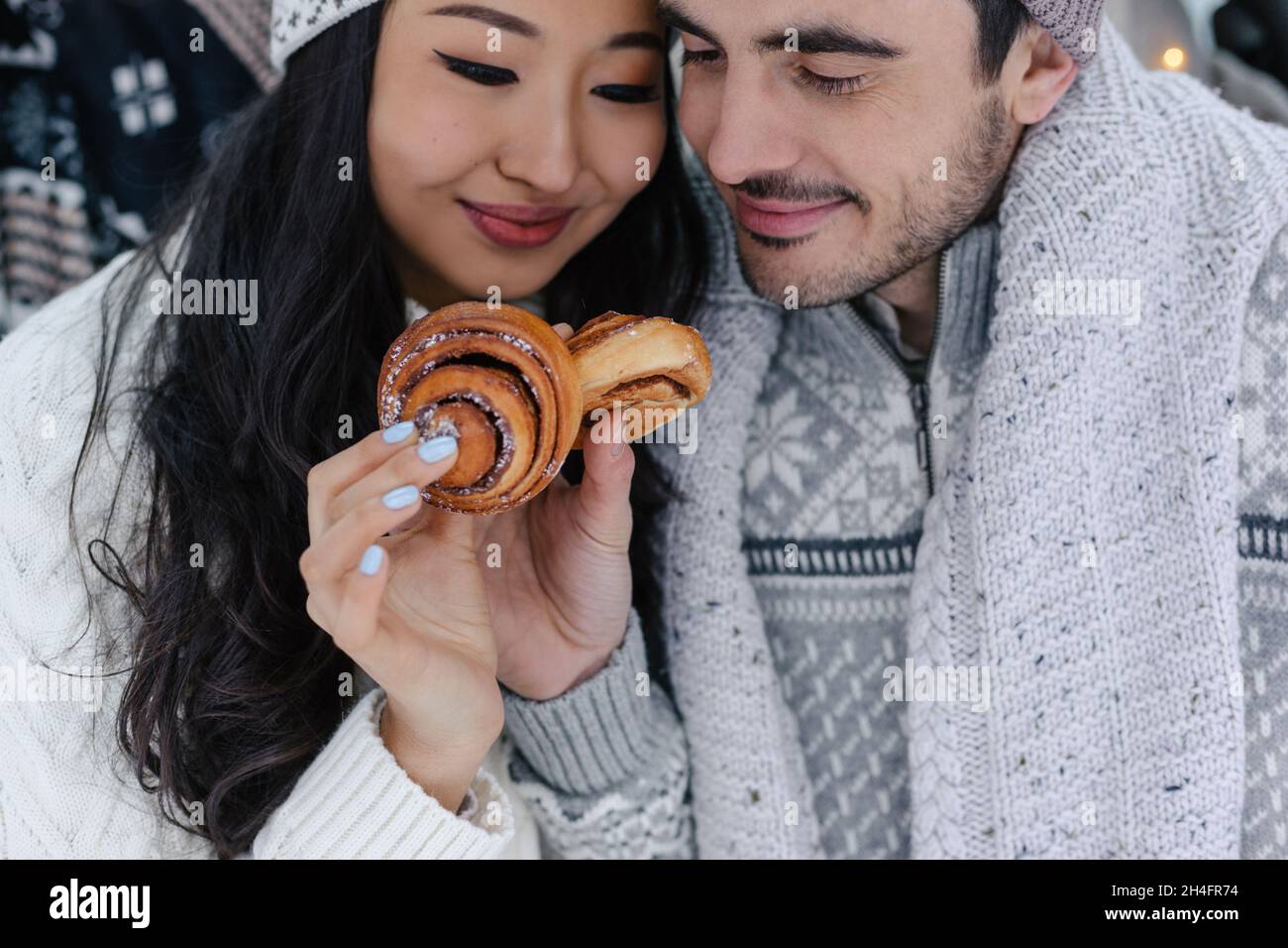 Coppia carina che ha picnic Foresta d'inverno che mangia Buns dolci. Picnic natura. Data storia dell'amore in macchina. Primo piano verticale Foto Stock