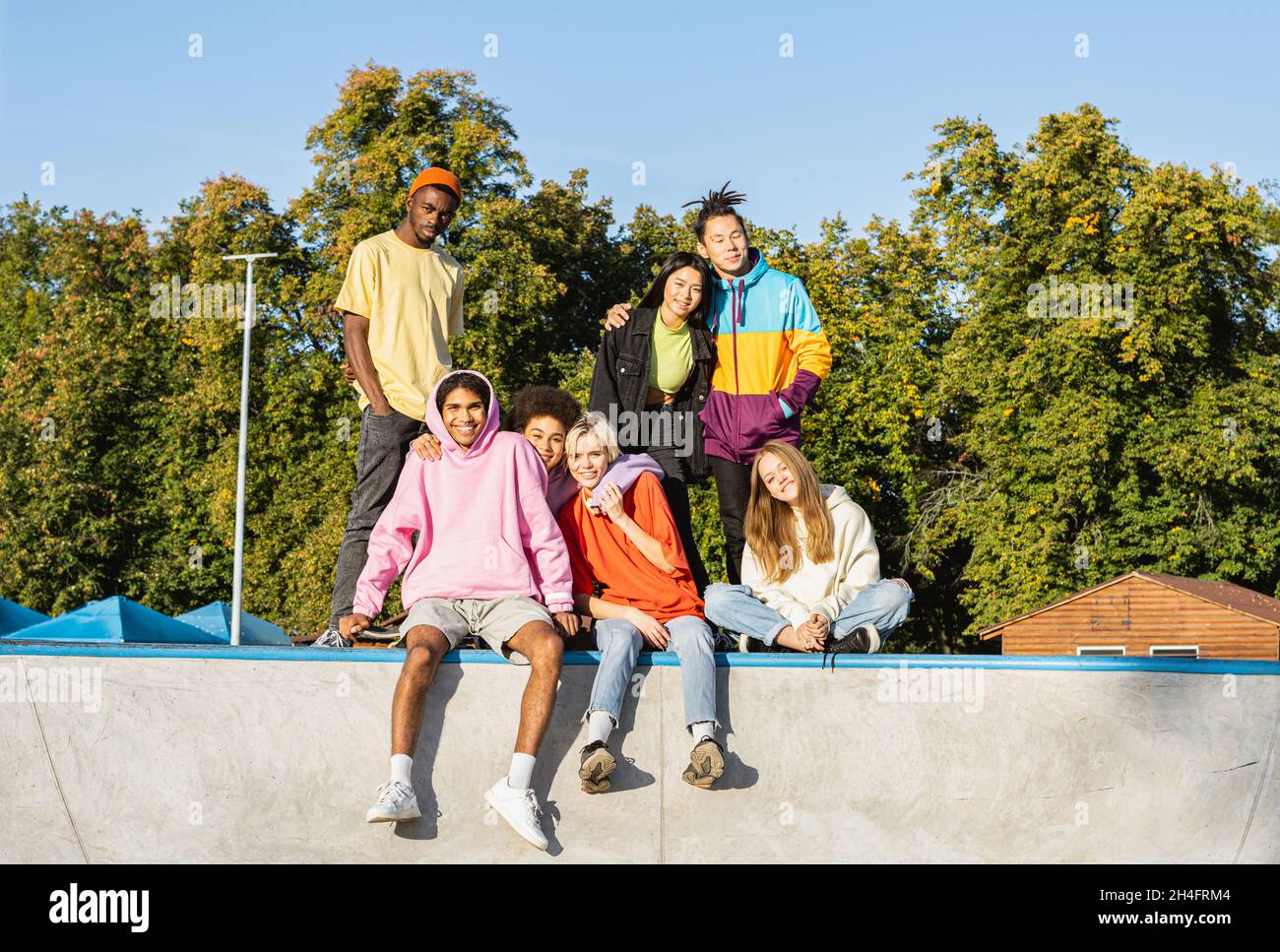 Gruppo multiculturale di giovani amici che si legano all'aperto e divertirsi - ragazzi alla moda e cool che si riuniscono al parco urbano skate Foto Stock