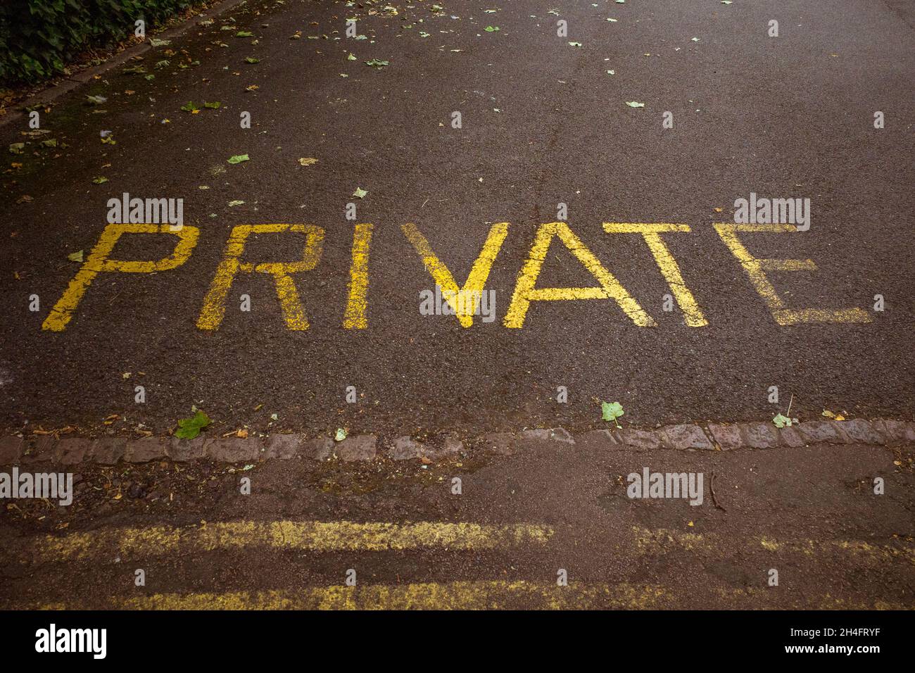 La parola privato dipinto su una strada in giallo vernice. Foto Stock