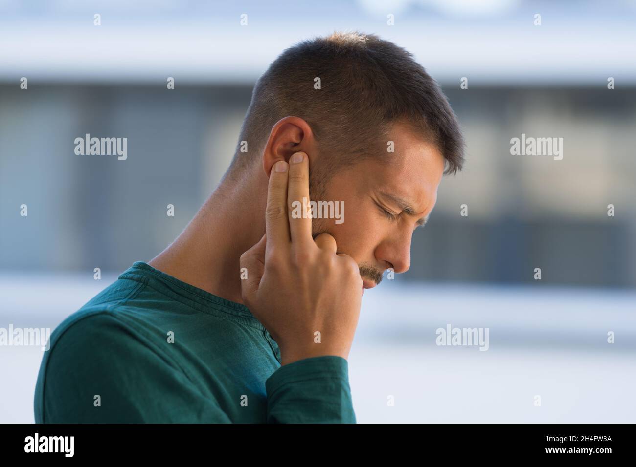 Uomo con tinnito. Uomo che tocca l'orecchio a causa di un forte dolore all'orecchio o all'orecchio. Otite Foto Stock