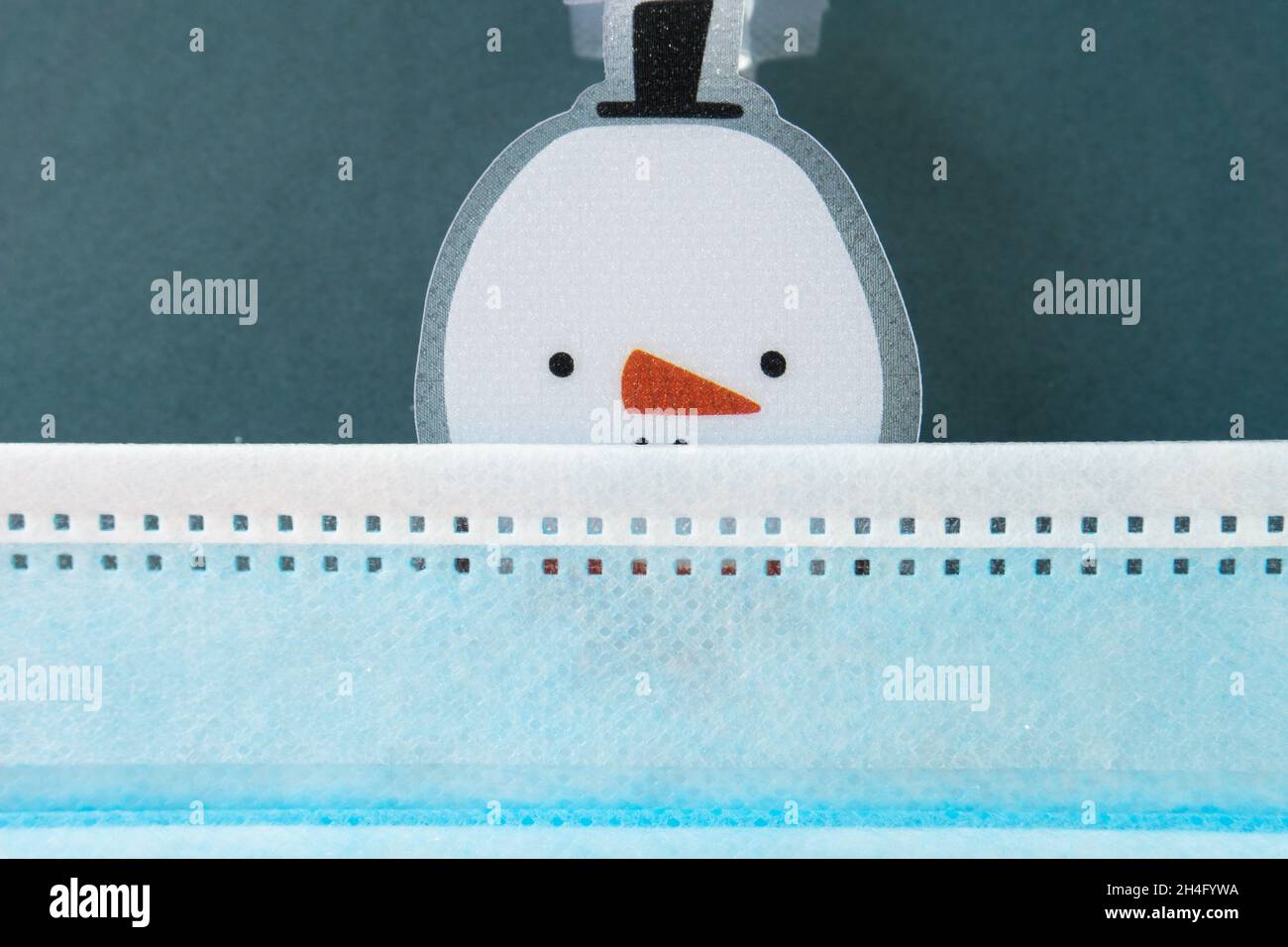 snowman sotto la maschera medica blu su sfondo verde. 2020 Natale. Foto Stock