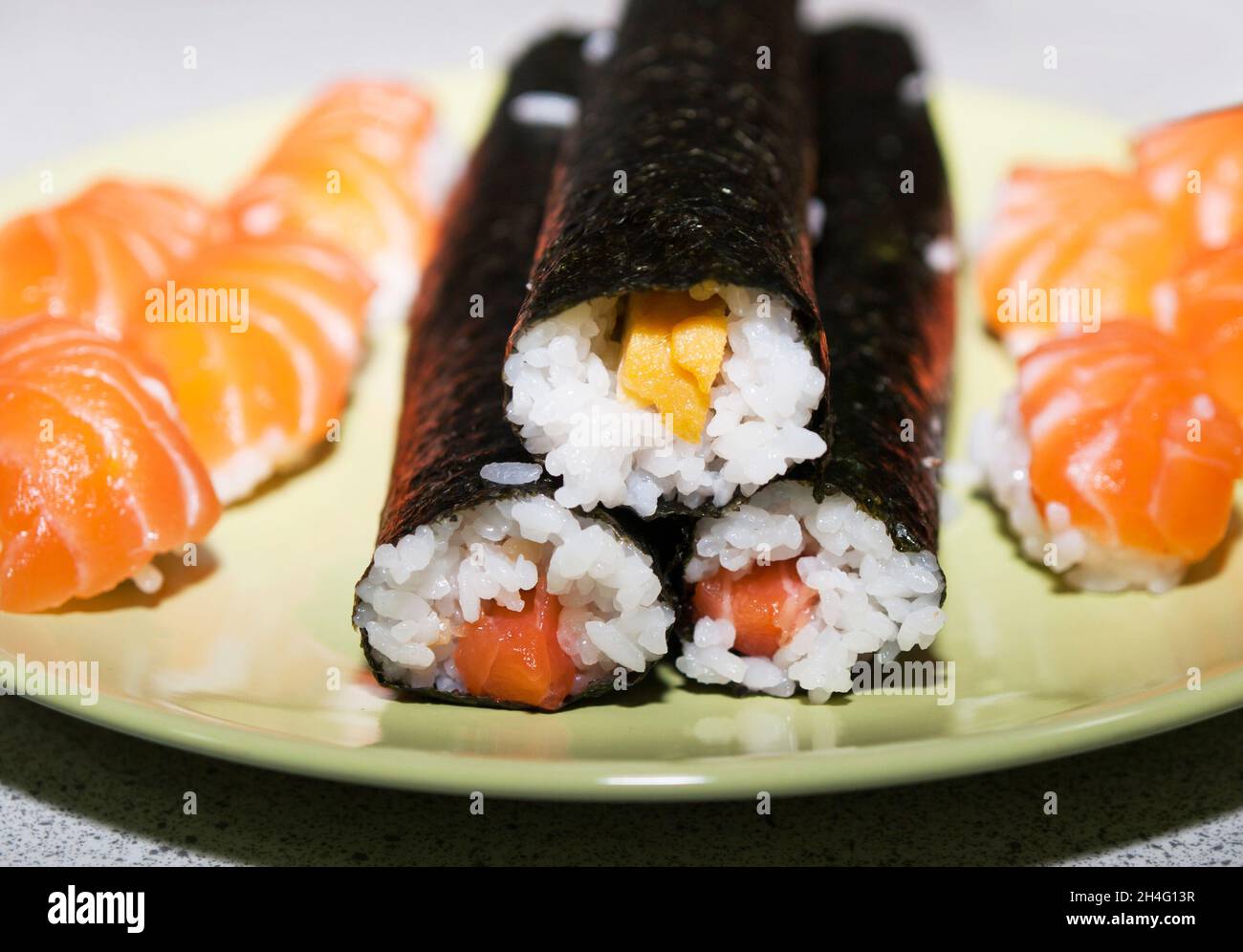 Il sushi tradizionale giapponese con salmone e uova preparati prima di tagliarlo a porzioni Foto Stock