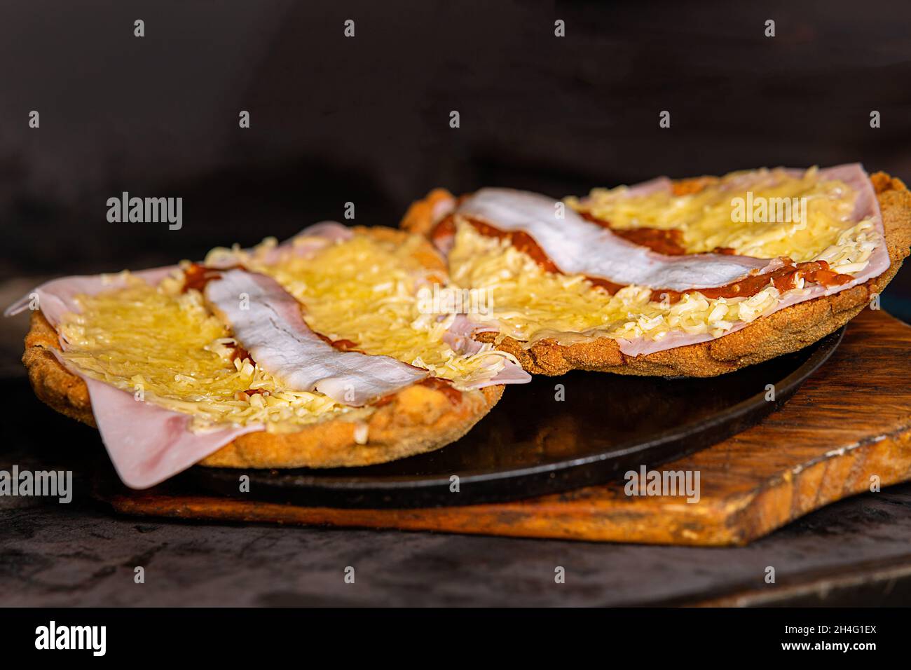 Primo piano di due metà di un pezzo con formaggio e pancetta su un piatto rotondo per preparare un hamburger Foto Stock
