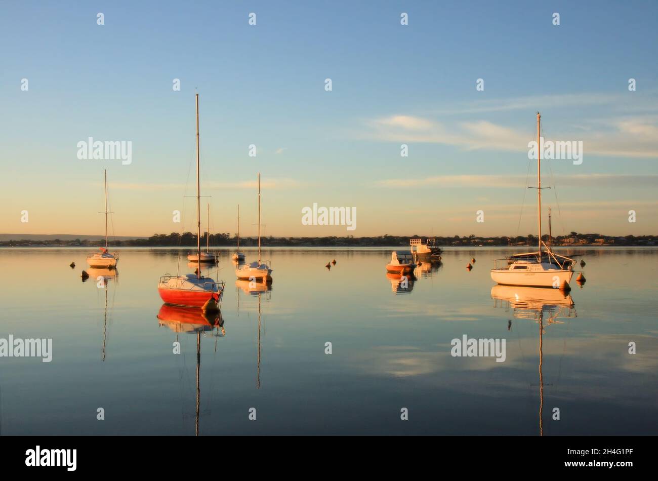 Yacht colorati con riflessi quasi perfetti nel tranquillo fiume Swan subito dopo l'alba a Nedlands, Perth, Australia Occidentale Foto Stock