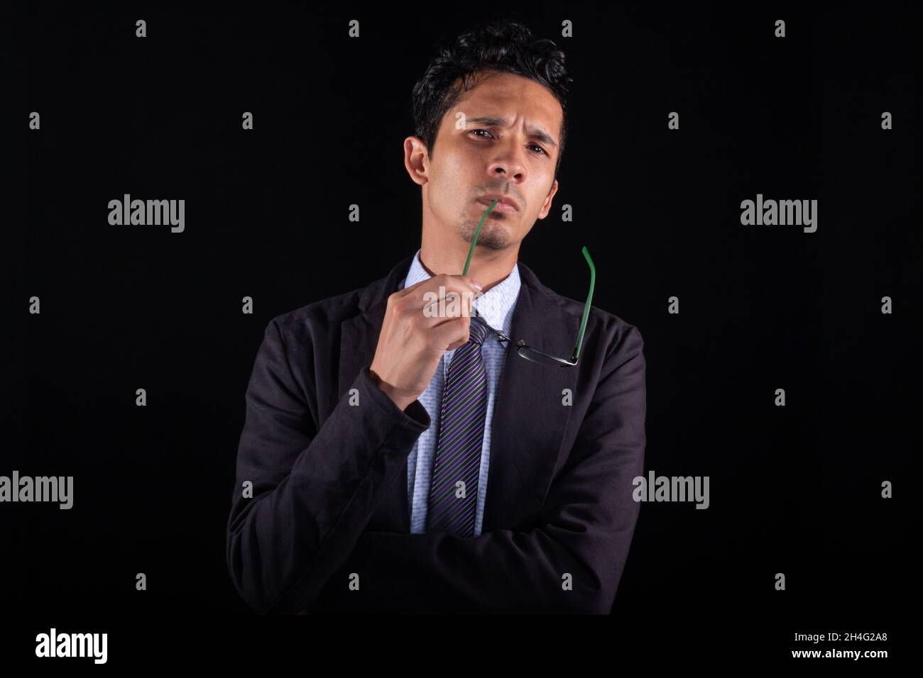 Uomo d'affari molto premuroso con occhiali in mano, isolato su sfondo nero. Concentrato giovane uomo d'affari guardando dritto avanti mentre Foto Stock