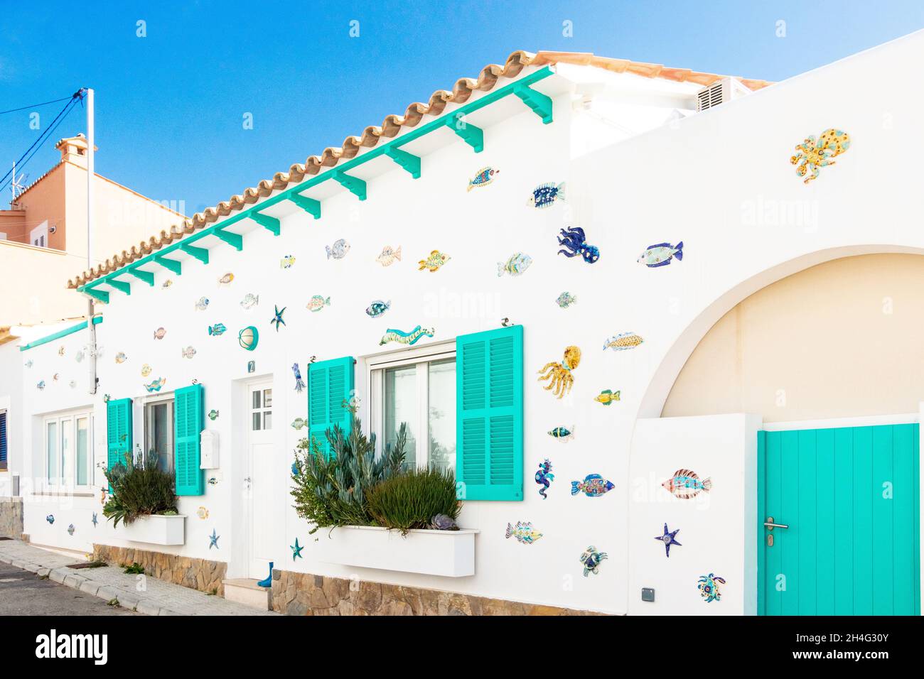 Casa sul mare dipinta di bianco con archi decorati con piastrelle a tema marino e oggetti a Sant Elm Mallorca Foto Stock