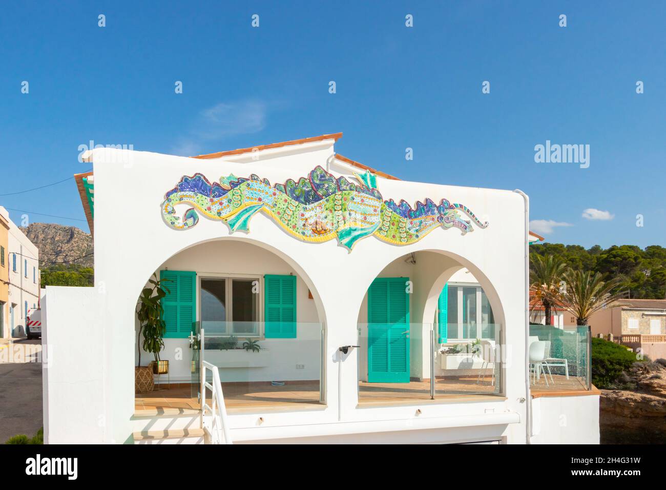 Casa sul mare dipinta di bianco con archi decorati con piastrelle a tema marino e oggetti a Sant Elm Mallorca Foto Stock