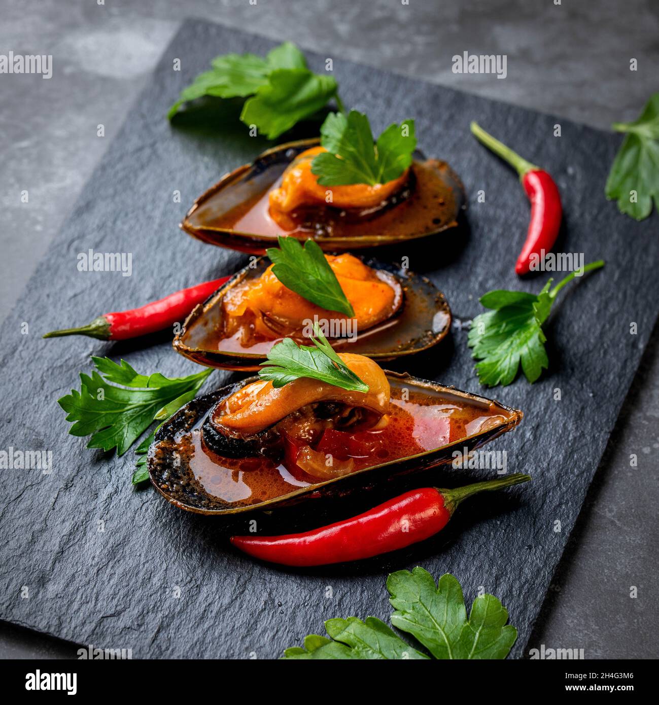 Cozze al vapore in salsa di pomodoro piccante Foto Stock