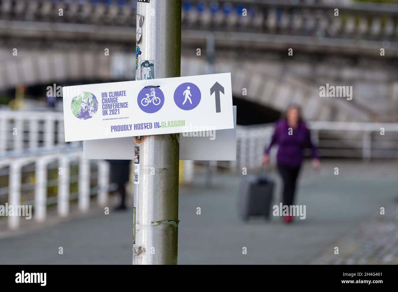 Donna con valigia a piedi sul lungomare Clyde dirigendo COP26 delegati a piedi o in bicicletta tra il luogo e il centro città, Glasgow, Scozia, Regno Unito Foto Stock