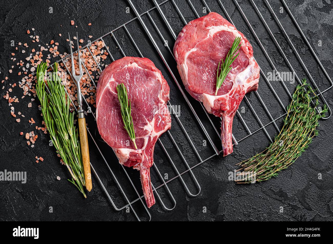 Bistecche fresche di manzo alla griglia con costolette di Tomahawk Raw. Sfondo nero. Vista dall'alto Foto Stock