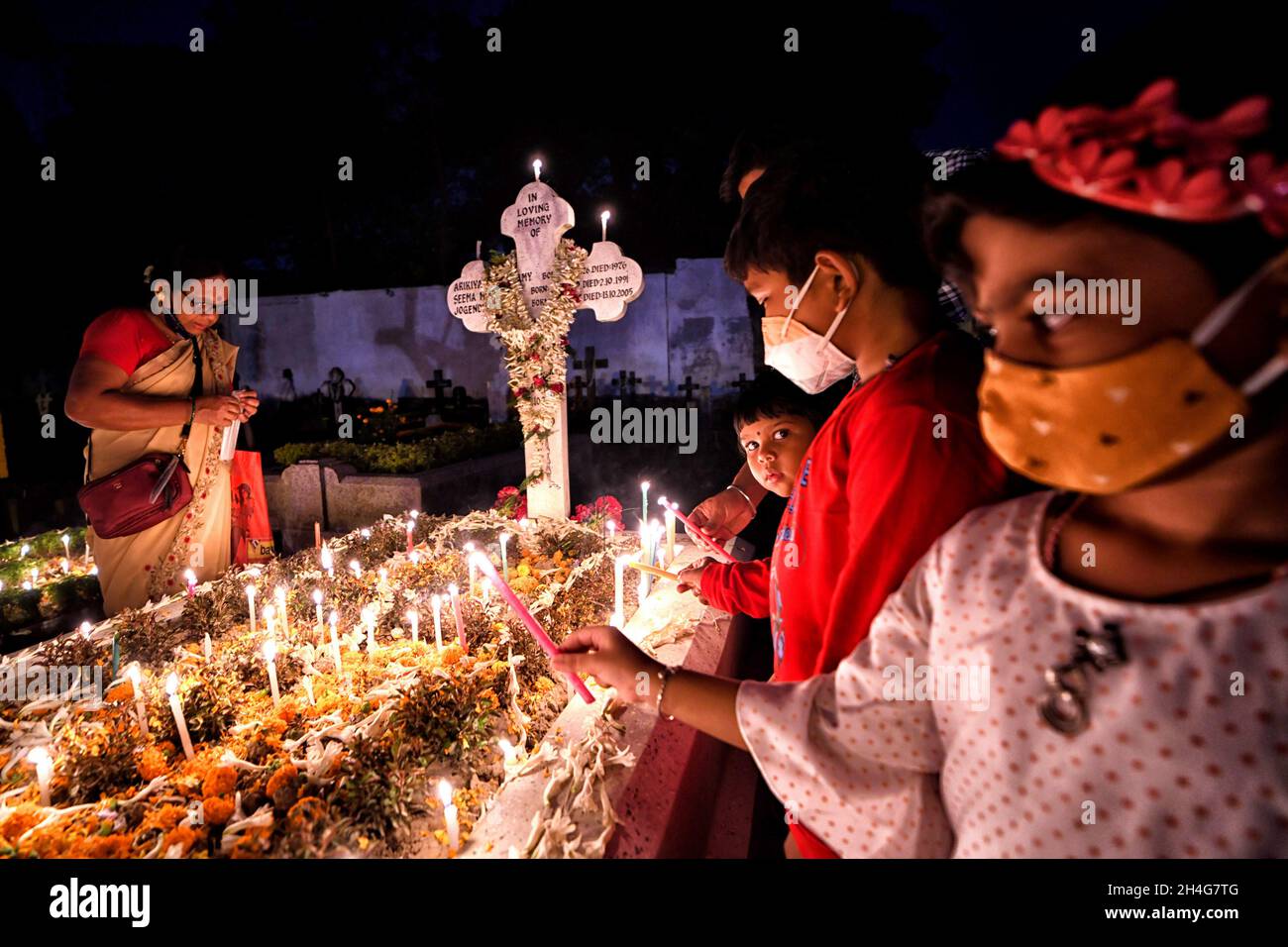 I bambini si accingono le candele accanto alla tomba del loro parente durante il giorno di tutte le anime a Kolkata.i devoti cristiani si radunano alle tombe dei loro cari nel cimitero con candele accese e fiori durante il giorno di tutte le anime. Un giorno in cui i cristiani ricordano i loro amici e parenti, che sono passati via. Ciò deriva da un'antica credenza che le anime dei morti ritorneranno, in questo giorno particolare, ad avere un pasto con la loro famiglia e amici. Le candele sono illuminate per guidare le anime alla loro casa per il pasto. (Foto di Avishek Das/SOPA Images/Sipa USA) Foto Stock