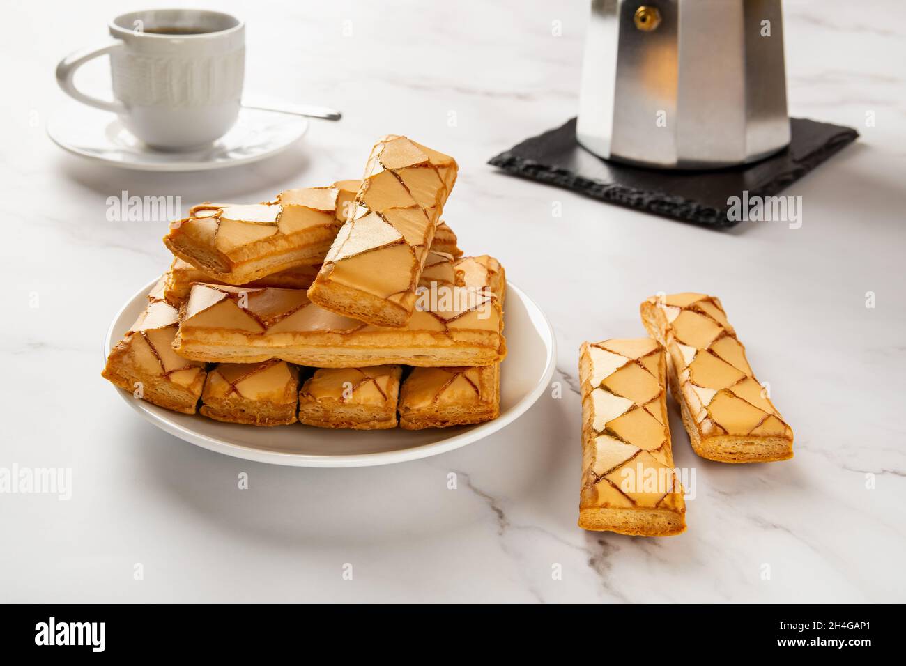 Panetteria italiana dolce croccante, vetrata di sfogliatine, macchina per il caffè geyser e tazza di caffè caldo sulla superficie di marmo. Colazione gustosa con pasticcini a base di pasta sfoglia. Foto Stock
