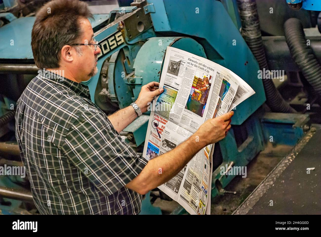 Un operatore stampa tira una copia del quotidiano per verificare la qualità dalla pressa Goss Urbanite a Columbus, Mississippi. Foto Stock