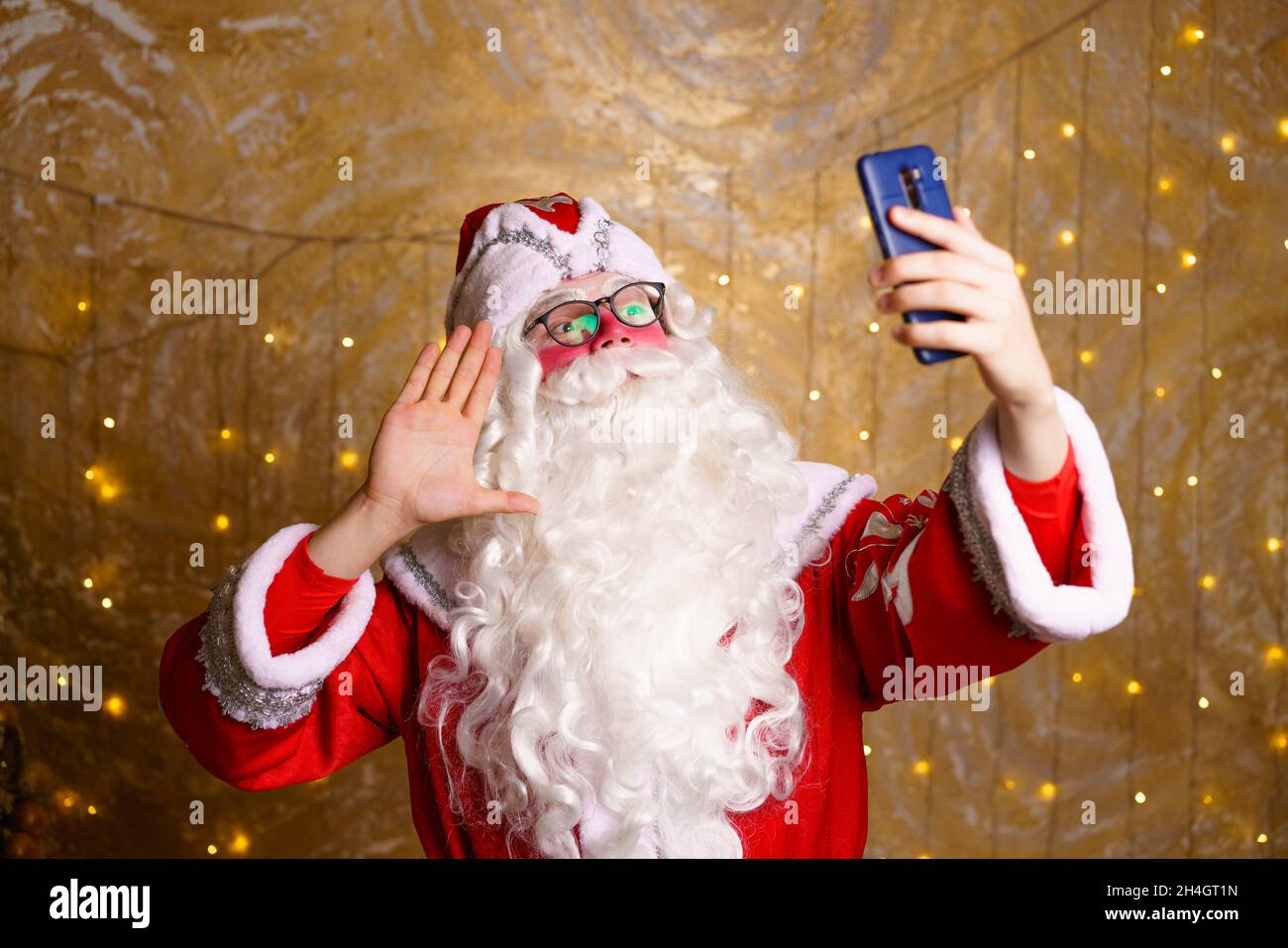 Babbo natale utilizzando il telefono cellulare durante il periodo di natale prende selfie o comunica tramite comunicazione video. Un regalo di natale di lusso o un regalo per un buon comportamento. Anno nuovo. Foto Stock