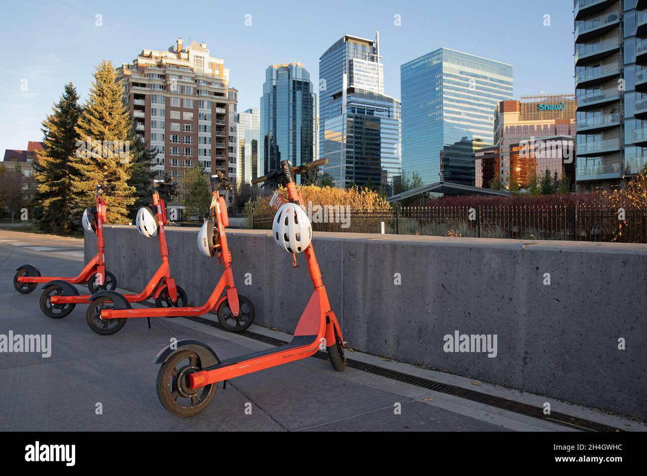 Fila di scooter condivisi a noleggio in centro, con il primo lucchetto con casco controllato da app al mondo per fornire un casco di sicurezza per ogni noleggio. Foto Stock