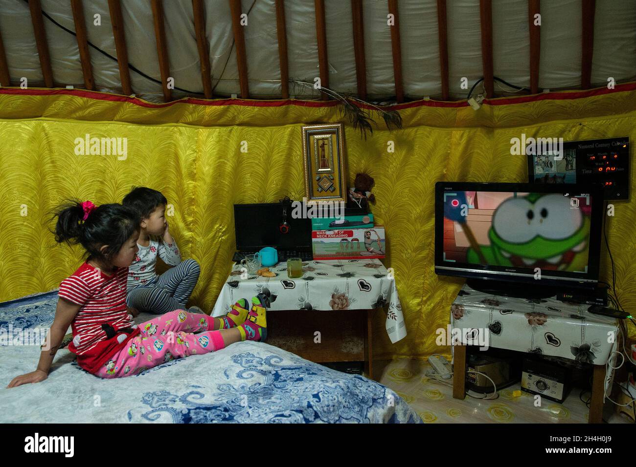 Shinebayar, 6 anni, e sua sorella Khngorzul, 4, guardano la TV a casa loro mentre la notte si avvicina in un quartiere di Ger della capitale Ulaanbaatar, 19 gennaio 2019. Foto Stock