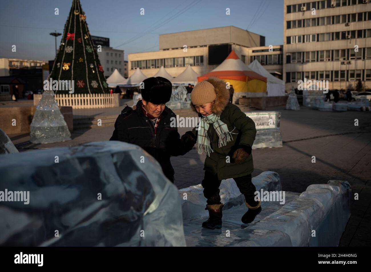 Un padre gioca con suo figlio su una scultura di ghiaccio nella capitale Ulaanbaatar, 22 gennaio 2019. Con le temeperature registrate che precipitano a -40 gradi Foto Stock