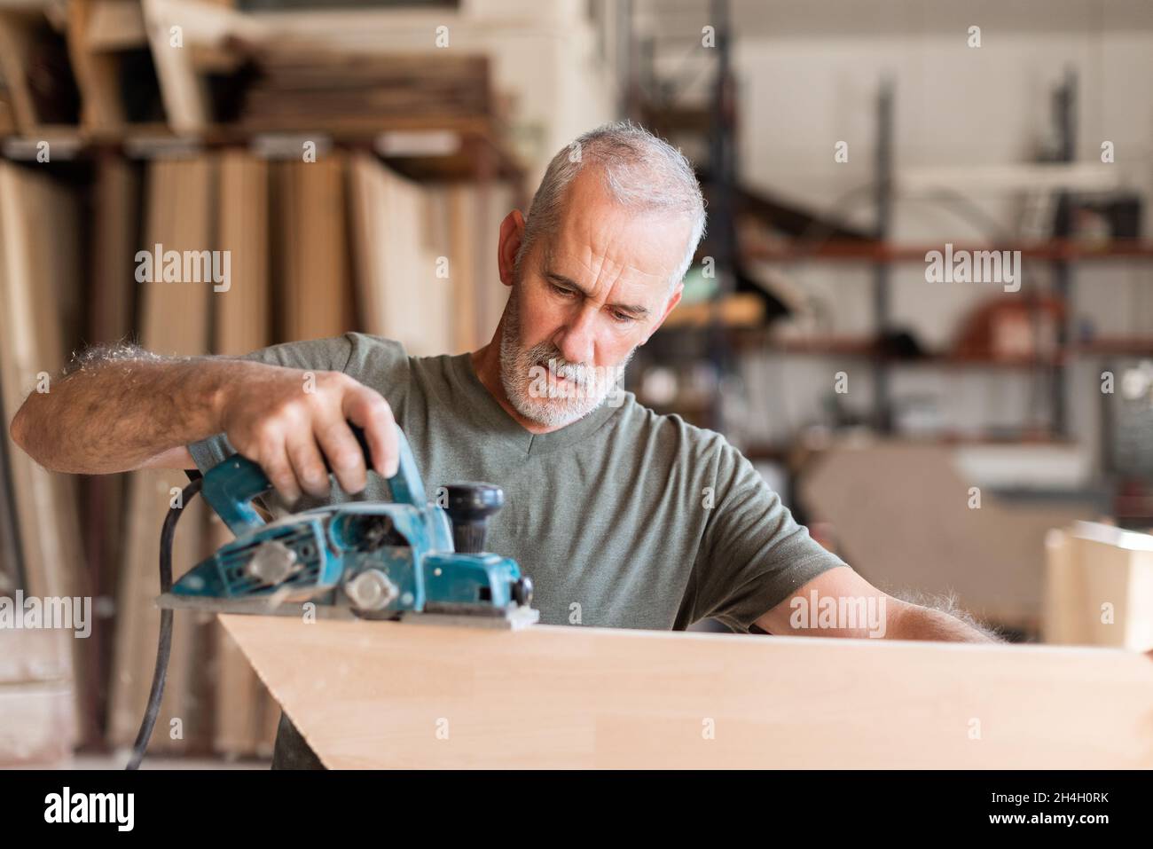 Uomo che pialla legno con una pialla manuale Foto Stock