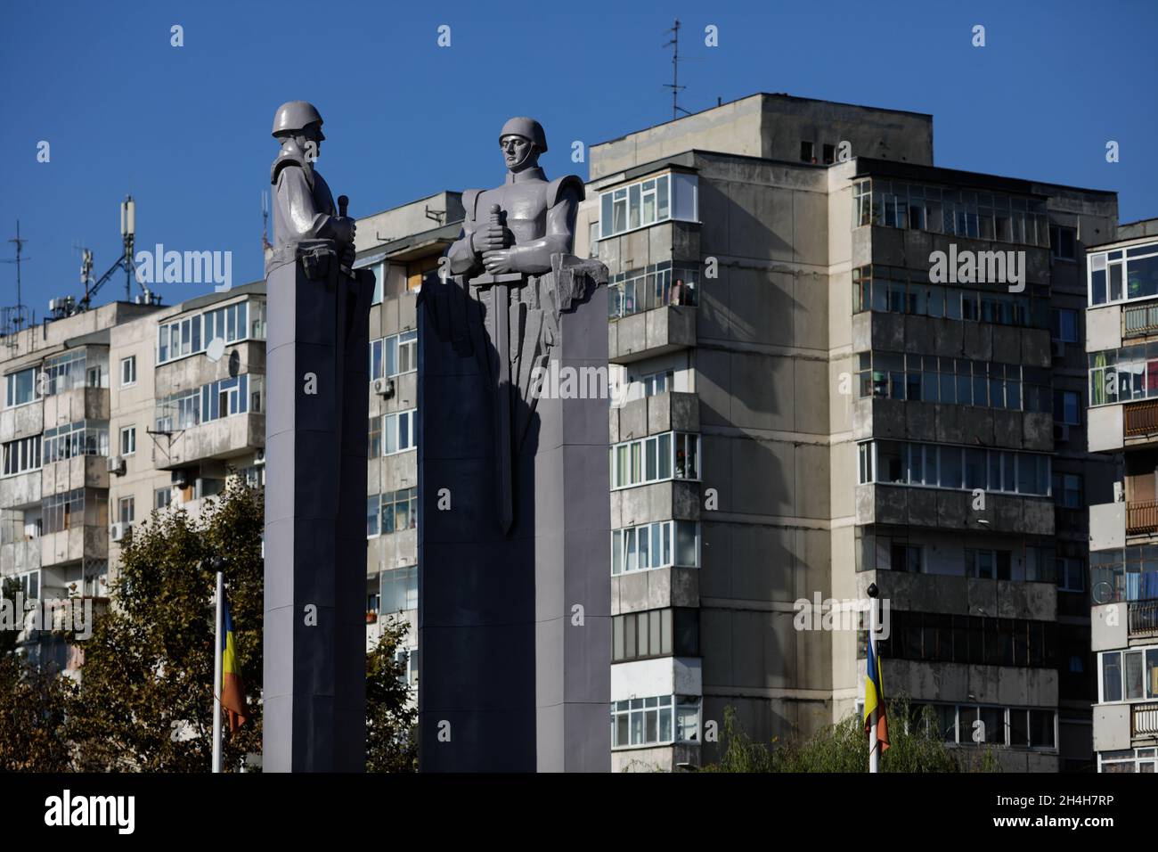 Bucarest, Romania - 27 ottobre 2021: Statua in stile comunista/sovietico raffigurante soldati con blocchi di appartamenti sullo sfondo. Foto Stock