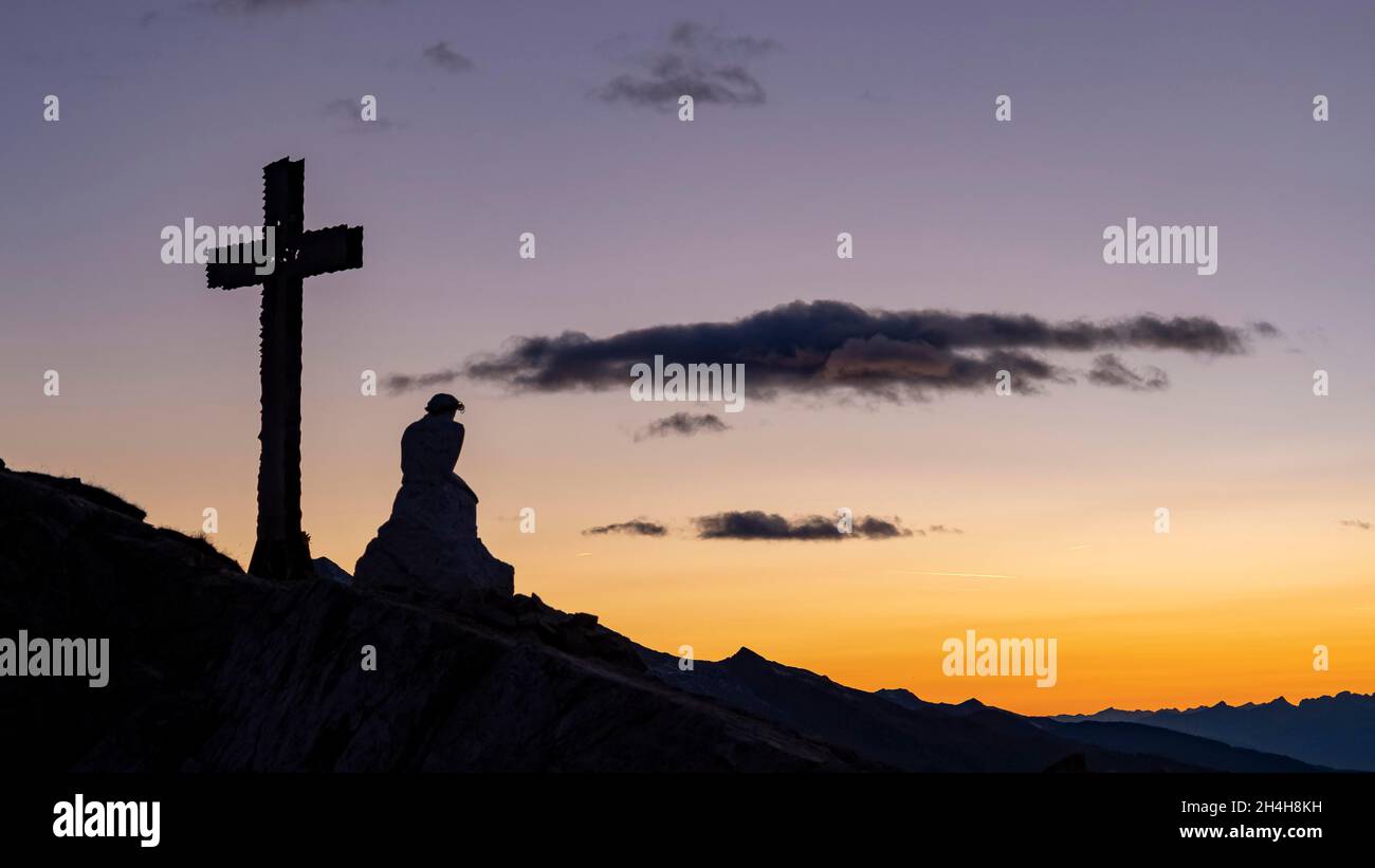 Croce di vetta e figura di Gesù sul Monte Castellaz, tramonto, Parco Naturale Paneveggio pale di San Martino, Rollepass, Trentino, Italia Foto Stock