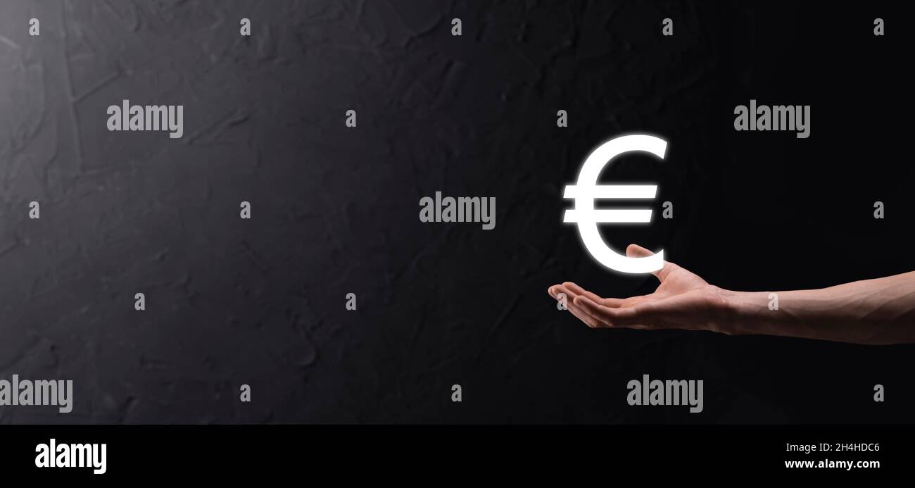 Businessman detiene denaro moneta icone euro o euro su sfondo scuro tono ..crescente concetto di denaro per gli investimenti e la finanza business. Foto Stock