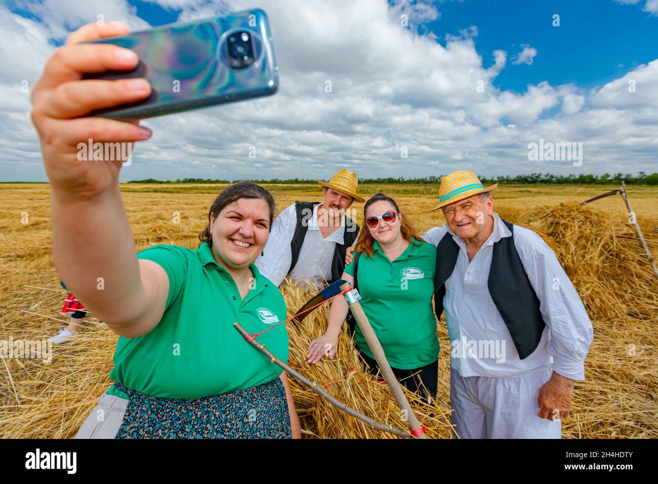 Muzlja, Vojvodina, Serbia, - 03 luglio 2021; XXXVIII tradizionalmente raccolto di grano. Donna prende selfie con i suoi amici dopo il raccolto, una foto in più per Foto Stock