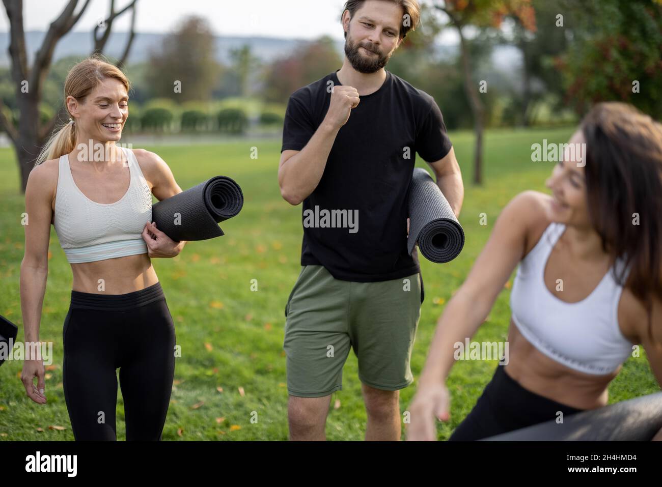 Le persone con materassini per il fitness si trovano in un prato verde Foto Stock