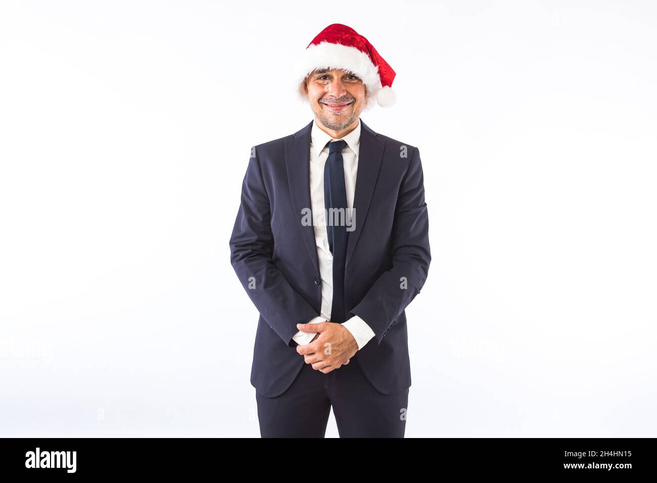 Uomo d'affari vestito in abito, cravatta e cappello di Natale di Babbo Natale, sorridente, su sfondo bianco. Concetto di festa di Natale. Foto Stock