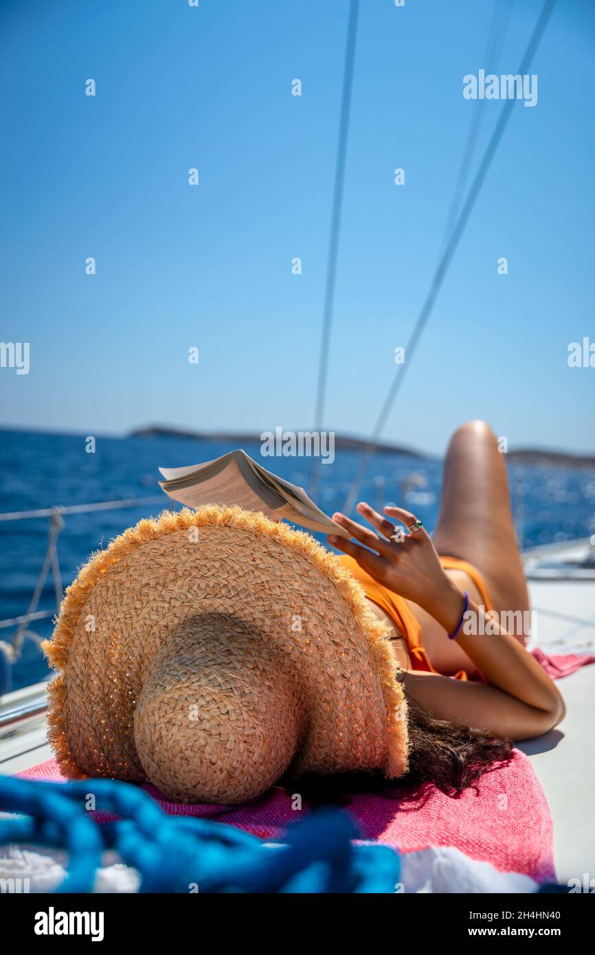 Traveler Girl con libro di lettura e abbronzatura di piacere sulla barca a vela. Vacanze estive attive. Viaggio in Grecia. Foto Stock
