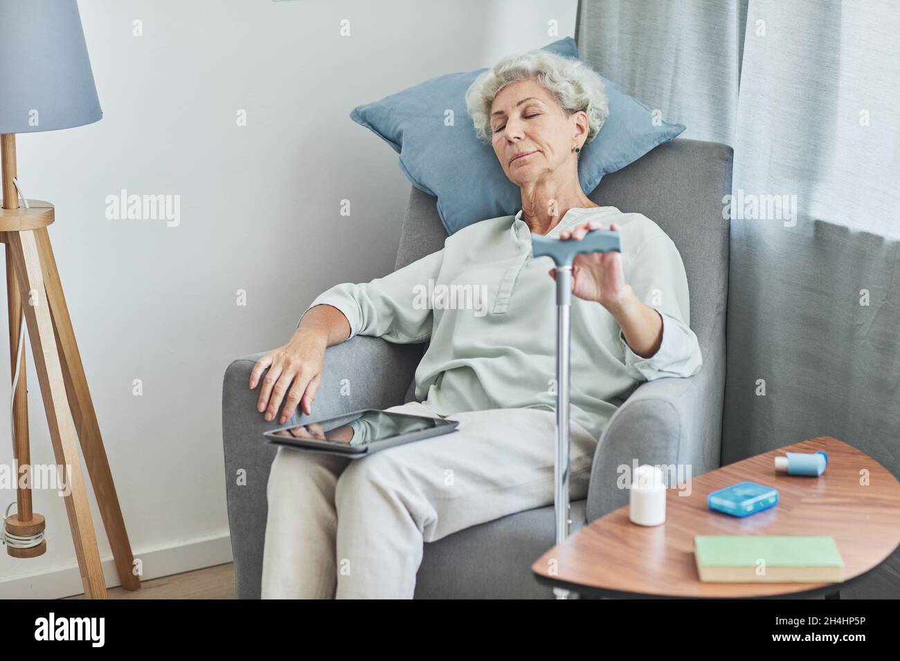 Ritratto di donna anziana con capelli bianchi che dorme in poltrona confortevole a casa con canna, spazio copia Foto Stock