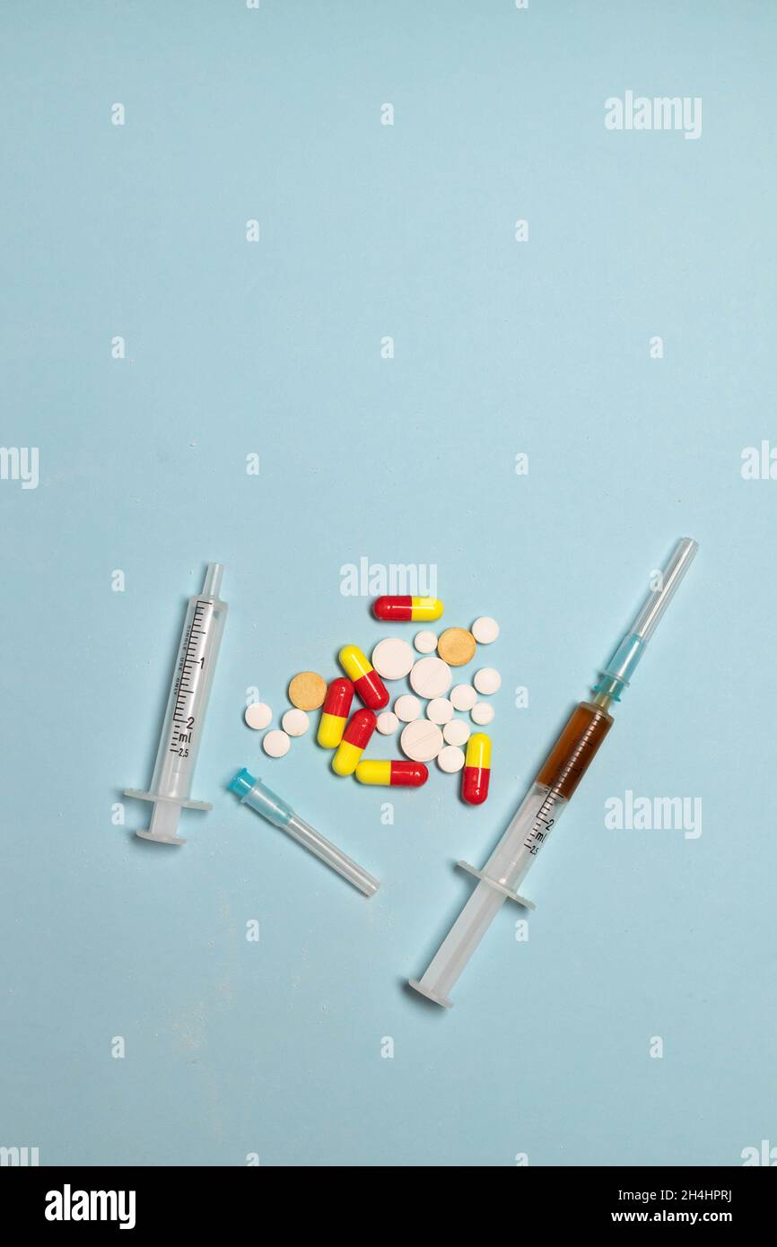 Farmaci pillole in polvere di eroina e siringhe su sfondo blu. Concetto di stile di vita sano. Giornata internazionale contro l'abuso di droga Foto Stock