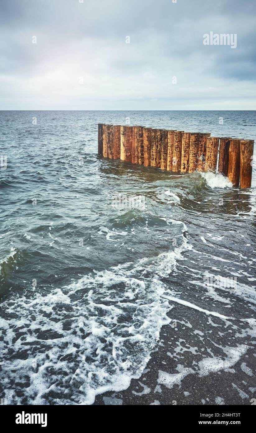 Breakwater di legno visto da una spiaggia, tonificante applicato. Foto Stock