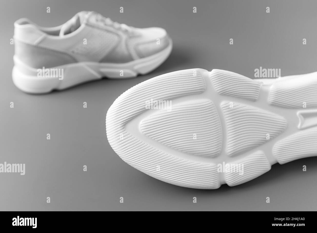 Due sneaker bianche da donna in pelle su sfondo grigio Foto Stock