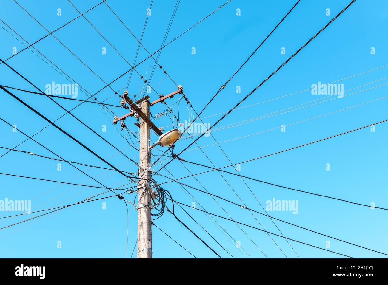 Polo elettrico con fili disordinati contro il cielo blu Foto Stock