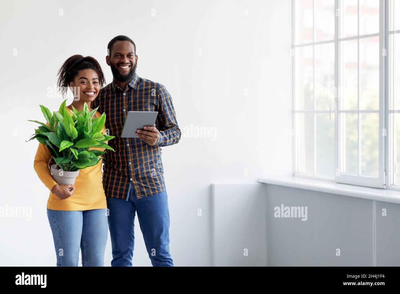 Allegro millenario coppia afroamericana che si muove in nuova casa e interni di pianificazione Foto Stock