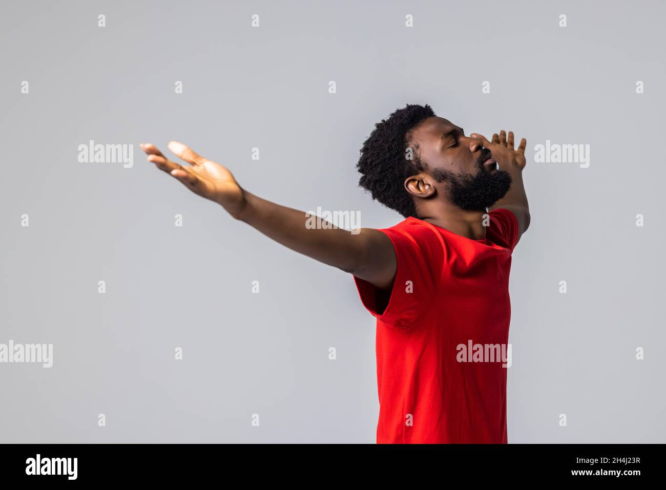 Il giovane uomo afroamericano trionfante festeggia la lotteria che scommette vincere urlando con gioia isolato su sfondo grigio Foto Stock