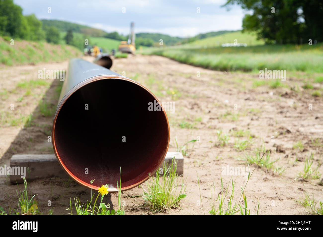 Un grande tubo di gas inutilizzato può essere visto in primo piano e porta allo sfondo sfocato con l'attrezzatura di posa del tubo nella figura Foto Stock