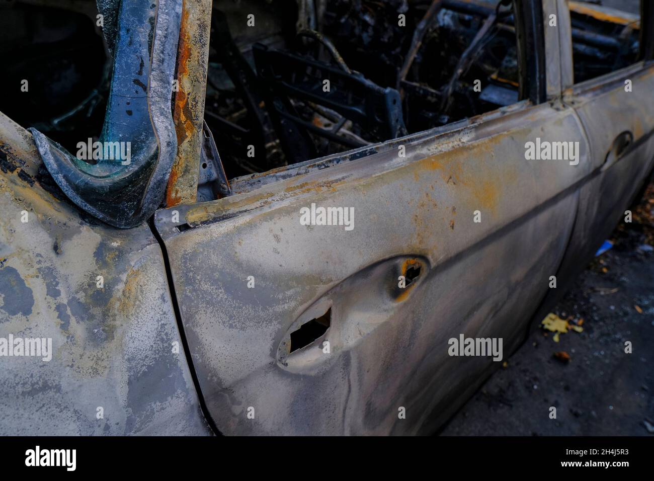 Porta dell'auto bruciata in primo piano. Sommossa, protesta civile, hooliganismo, criminale in città. Foto Stock