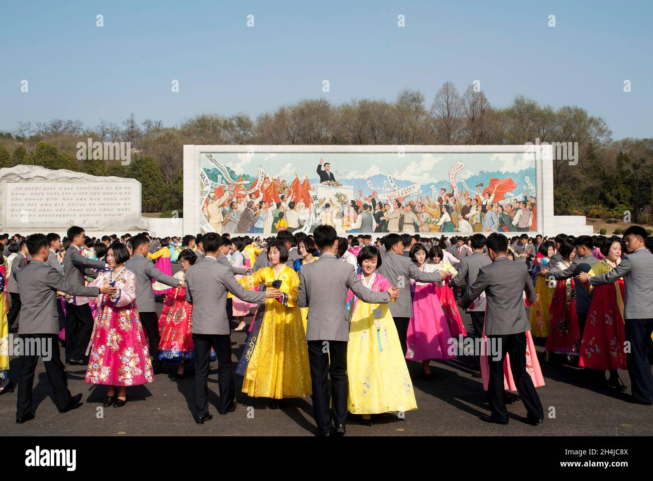 Gli studenti di Pyongyang ballano di fronte a un murale di Kim il-Sung per celebrare il giorno del Sole in Corea del Nord, aprile 2019 Foto Stock